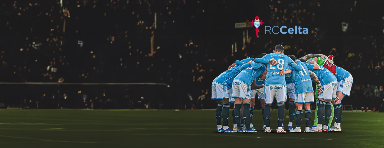 Jugadores del RC Celta de Vigo unidos sobre el césped con la grada de fondo